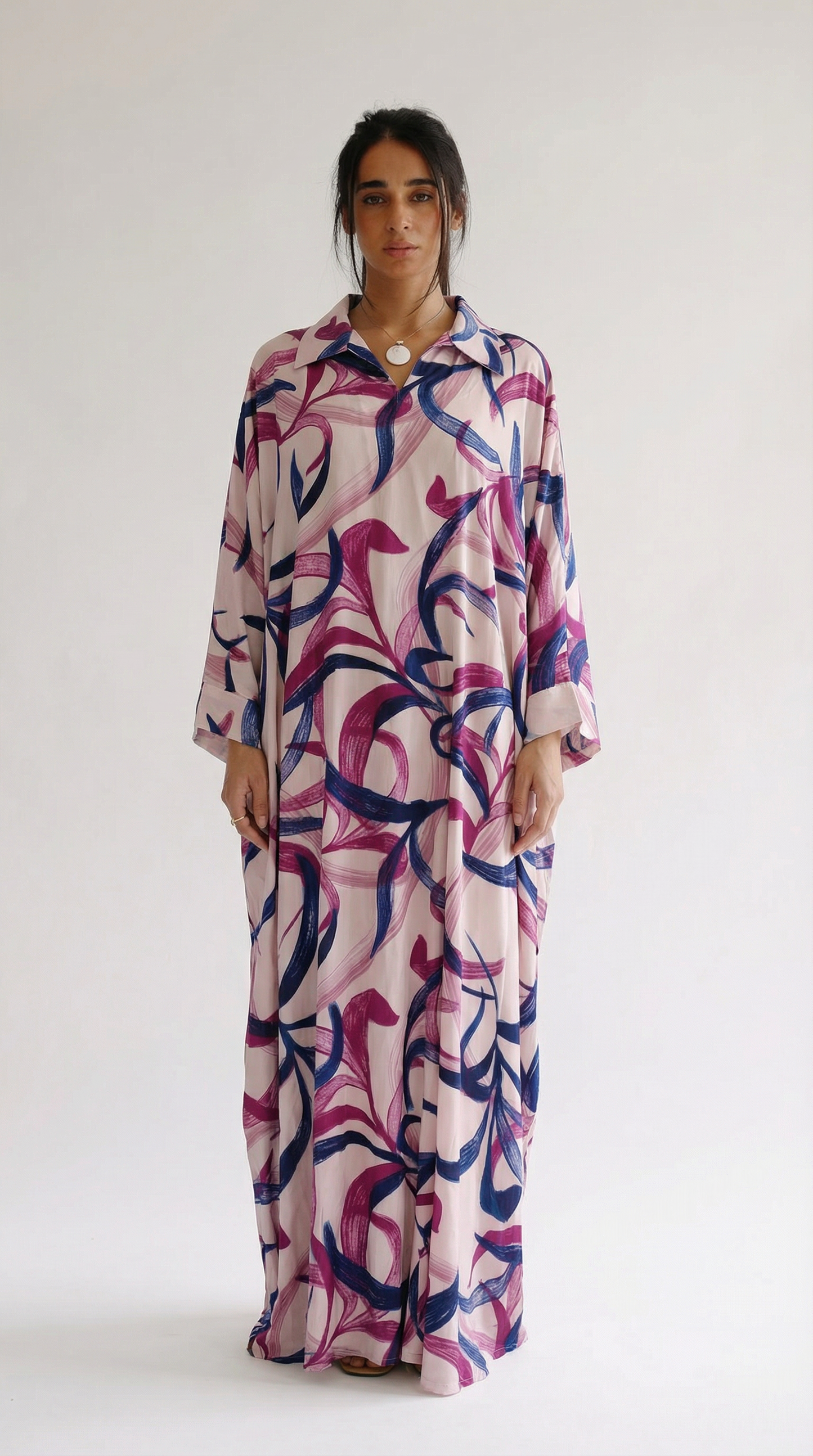 Woman wearing a long, patterned dress against a white background