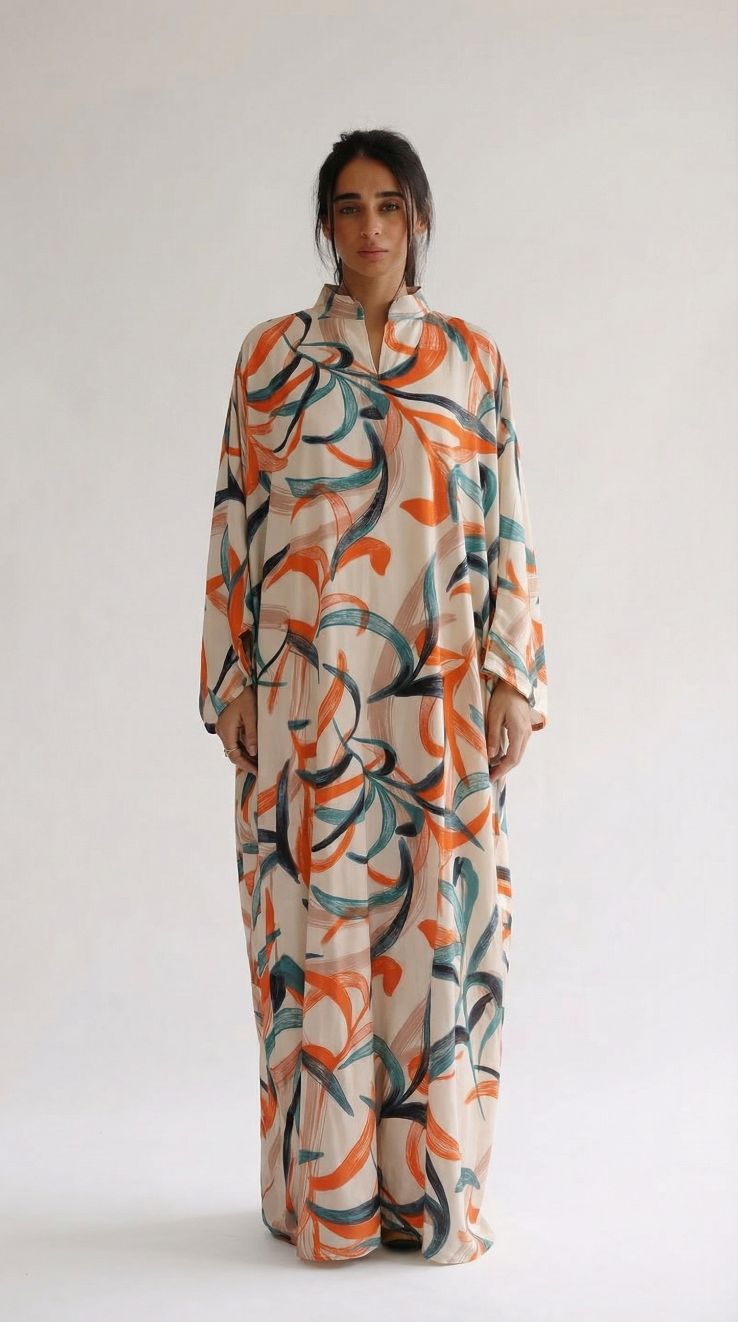 Woman wearing a long, patterned dress against a white background