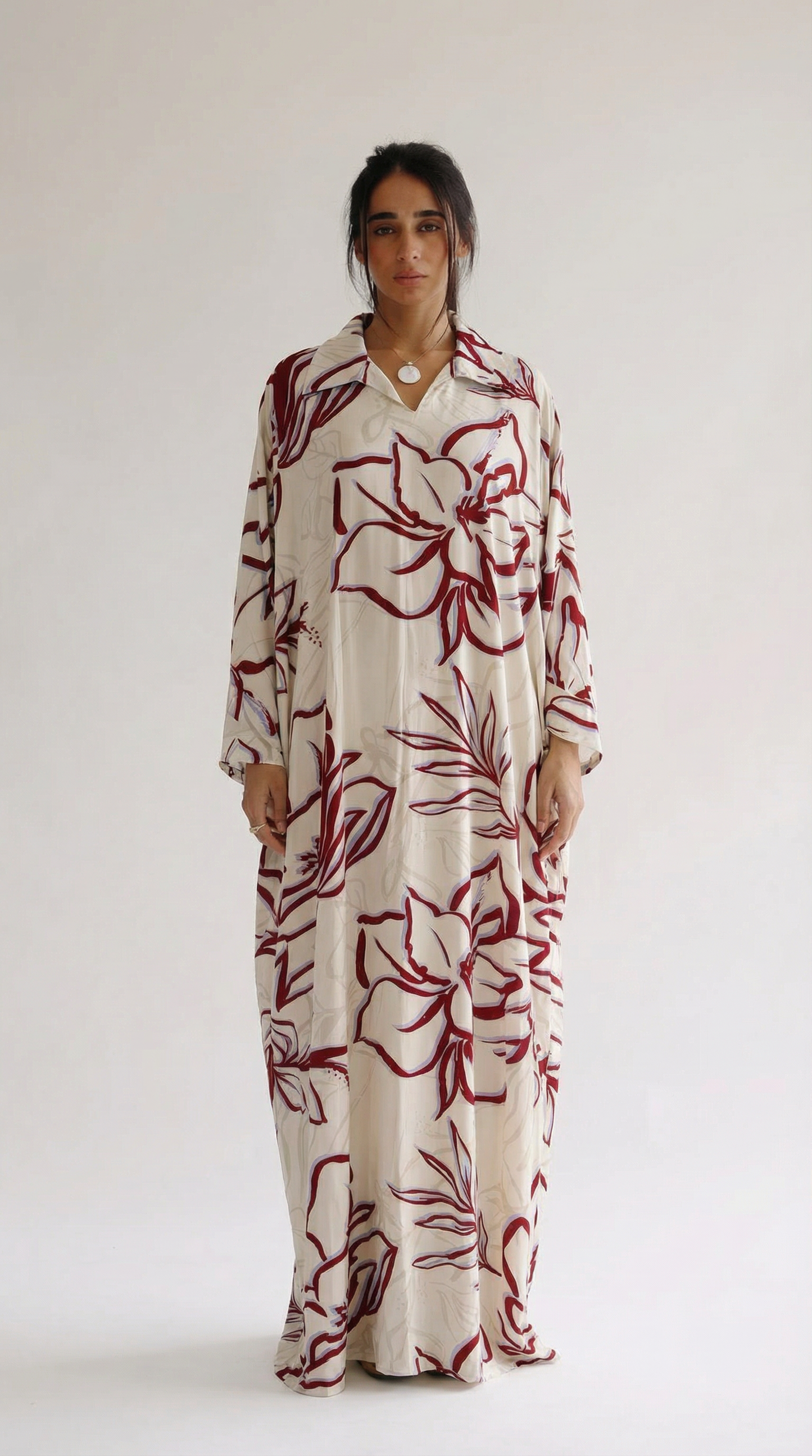 Woman wearing a long floral dress with red flowers on a white background