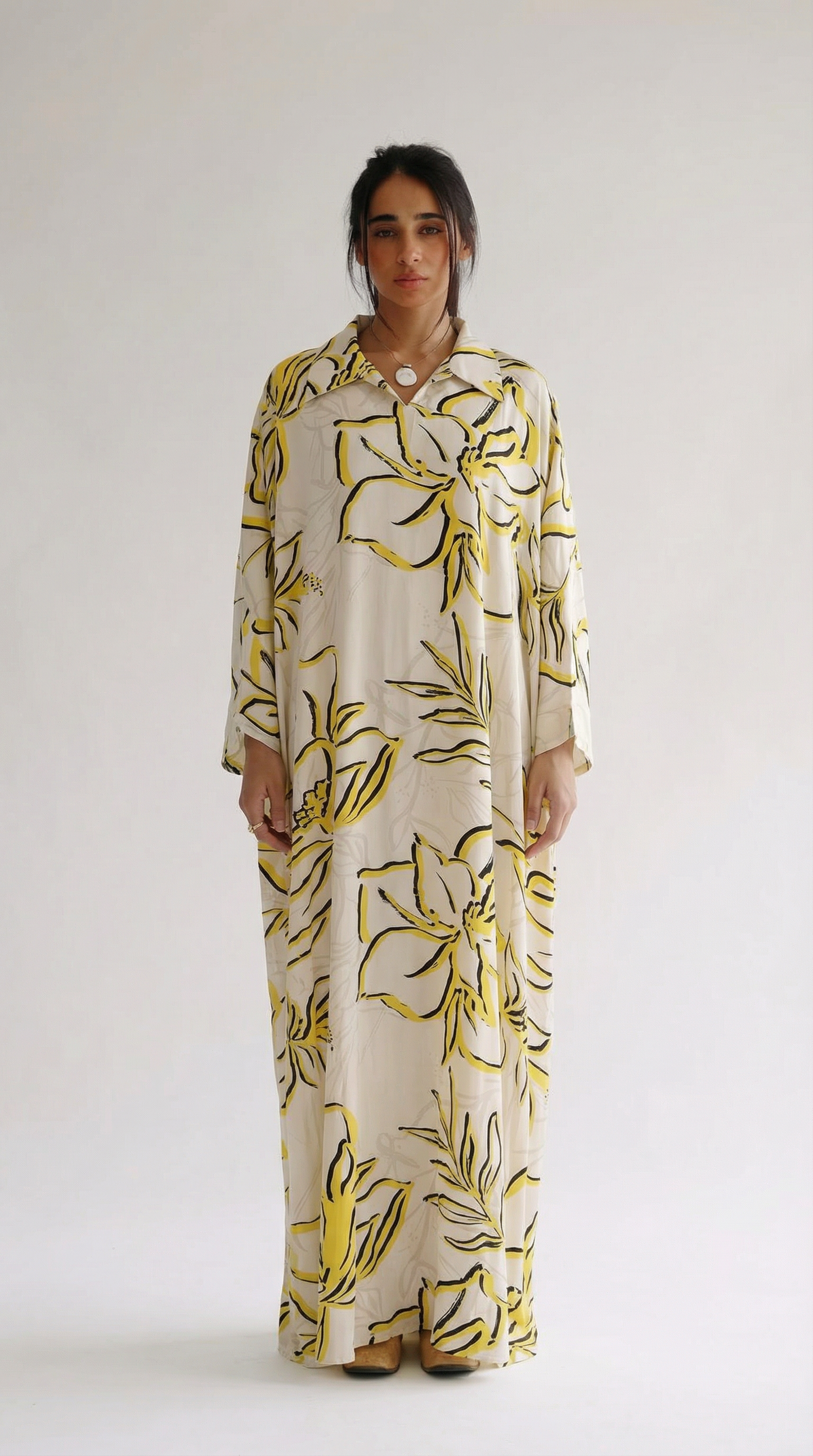 Woman wearing a long floral dress with yellow flowers on a white background
