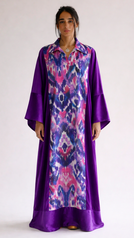 Woman wearing a long, patterned dress with a purple base and multicolored design on a white background