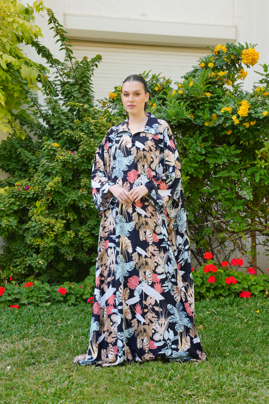 Woman in a floral dress standing outdoors with greenery and flowers in the background