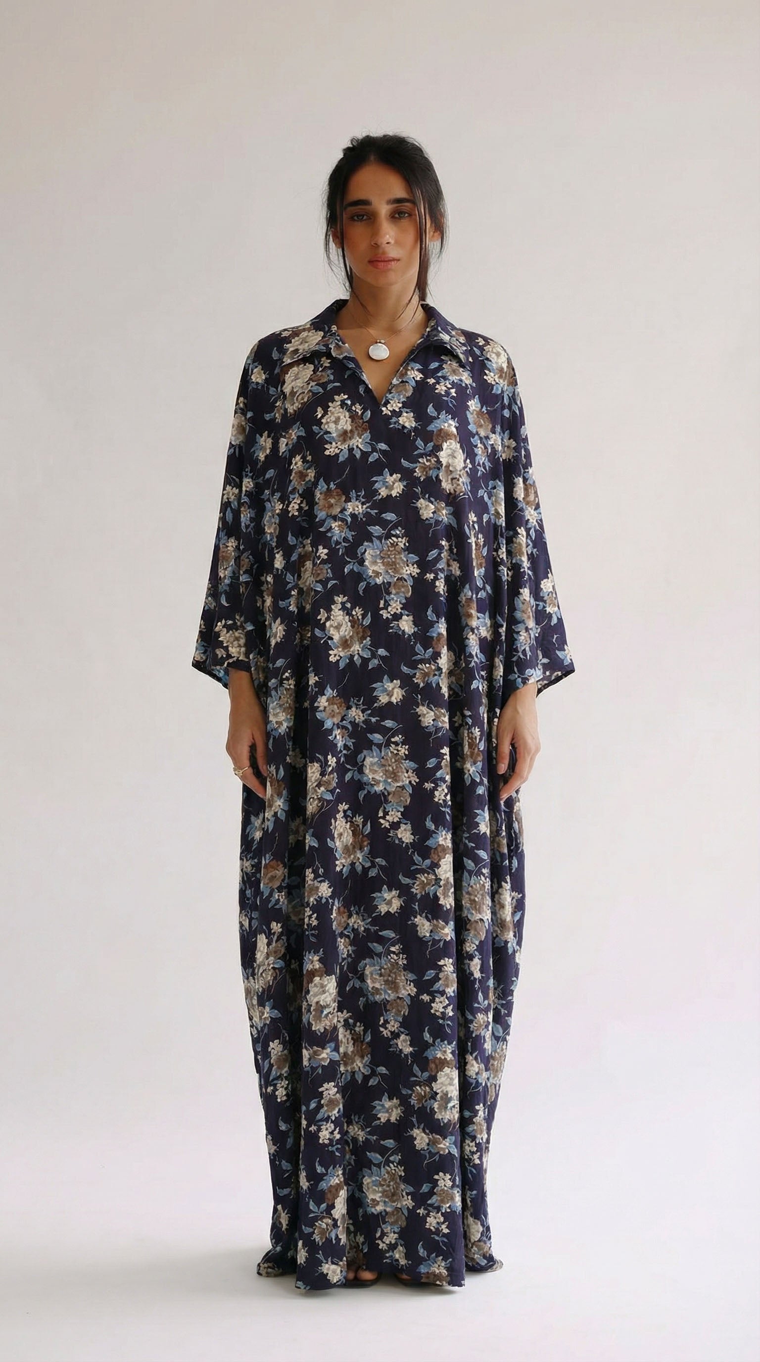 Woman wearing a long floral dress against a white background
