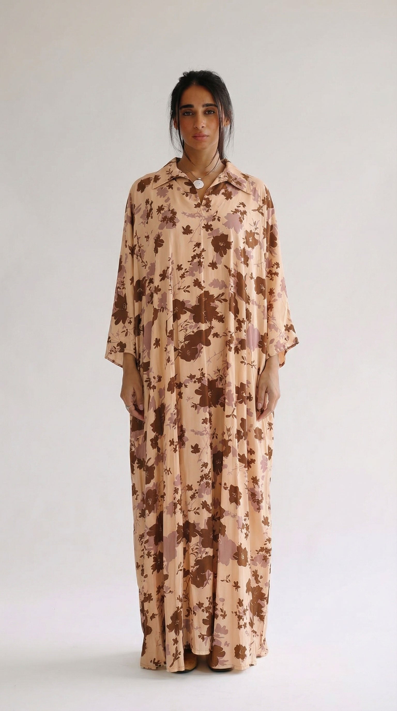 Woman wearing a long, floral-patterned dress against a white background
