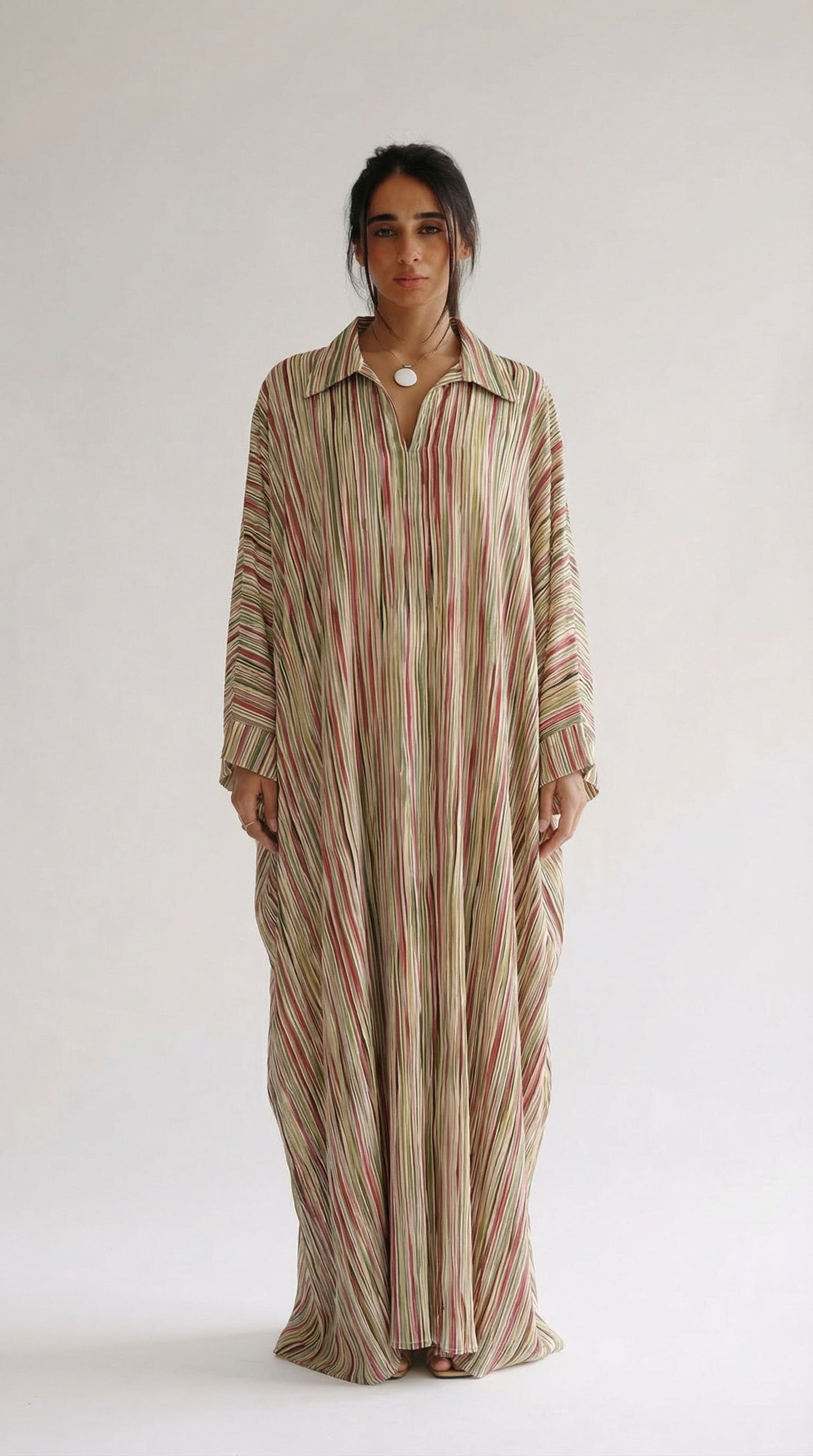 Woman wearing a long, striped dress against a white background