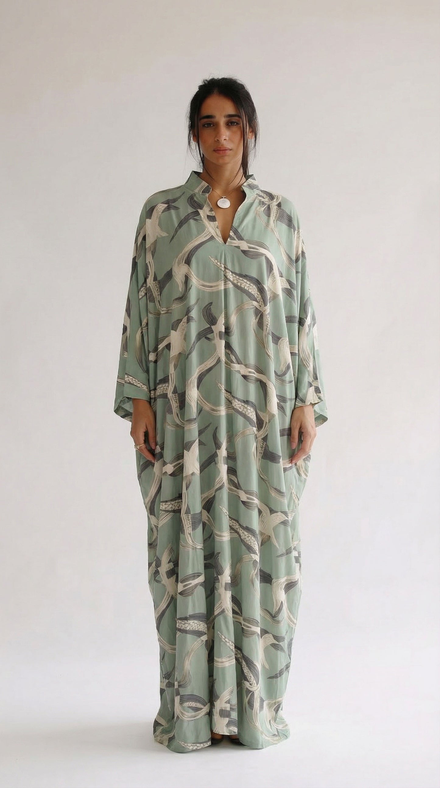 Woman wearing a long, patterned dress against a white background