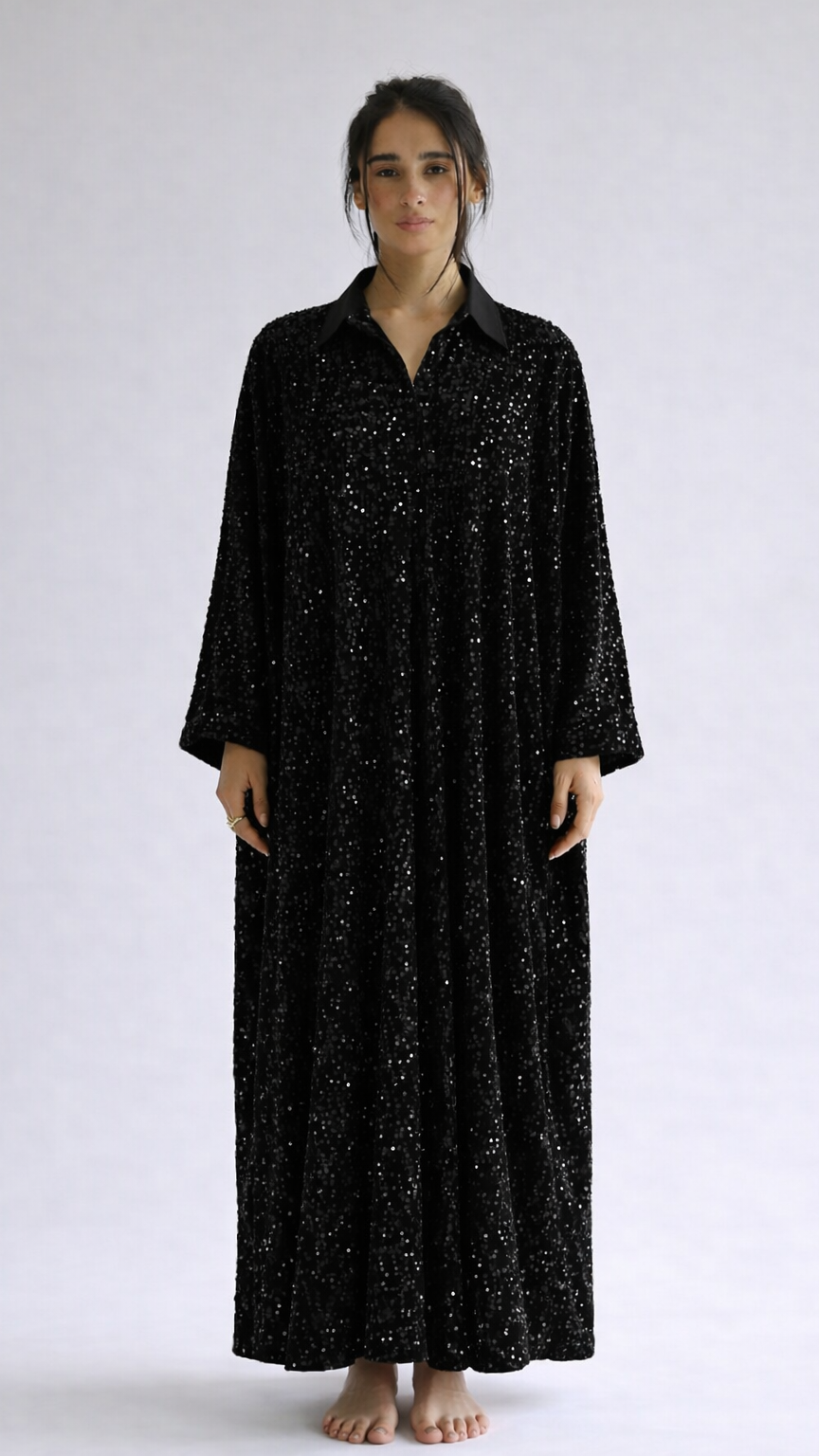 Woman wearing a black long-sleeve dress with a subtle pattern on a white background