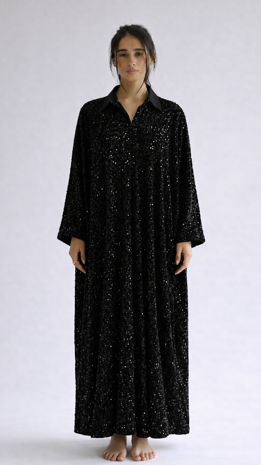 Woman wearing a black long-sleeve dress with a subtle pattern on a white background