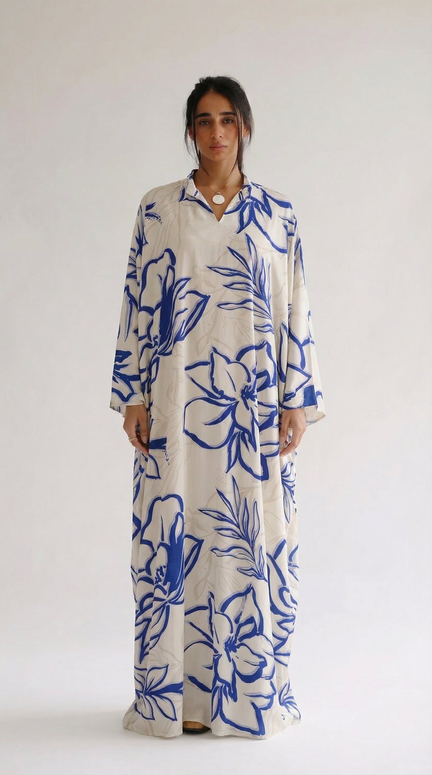 Woman wearing a long floral dress with blue and white pattern on a plain background