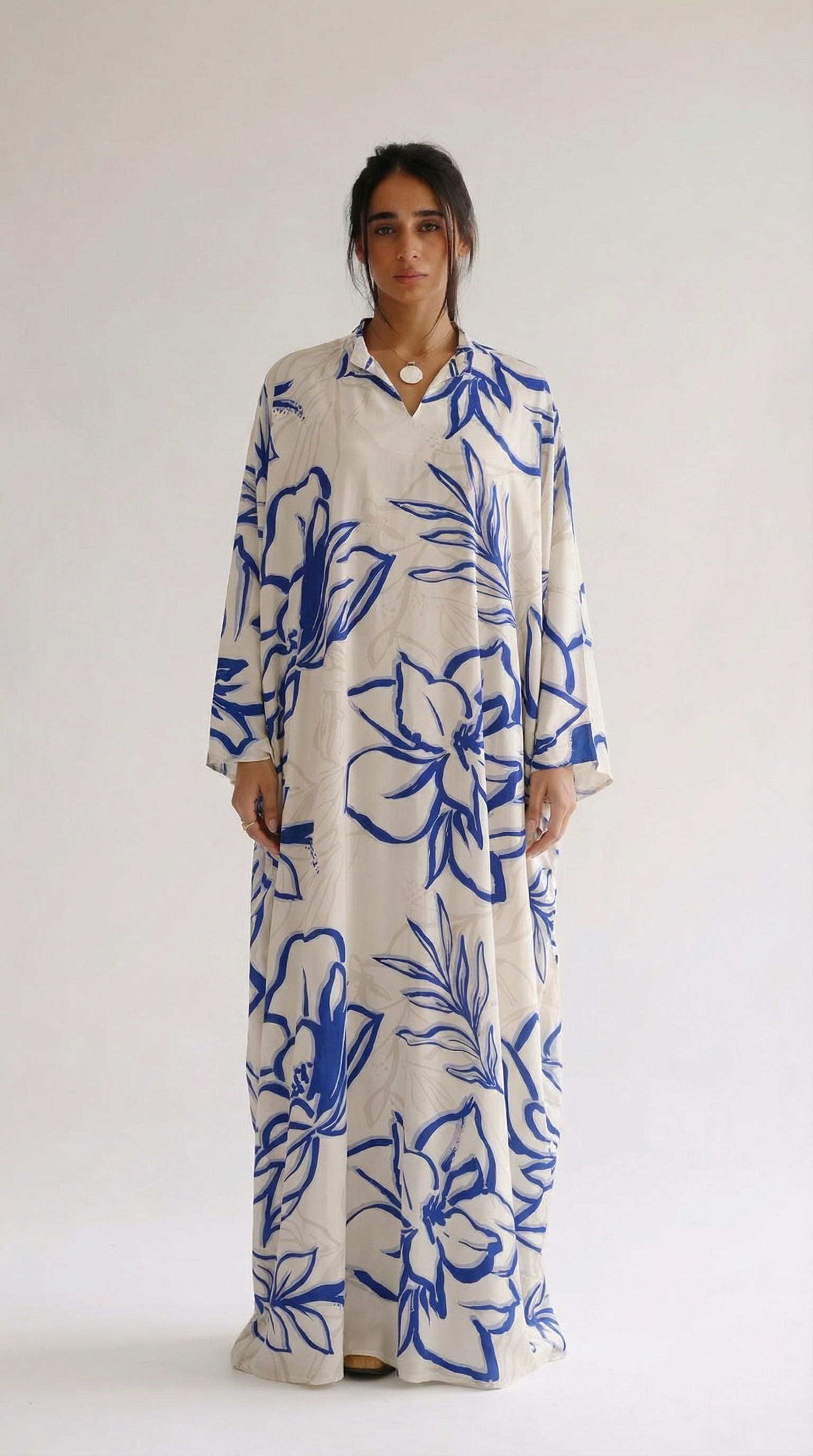 Woman wearing a long floral dress with blue and white pattern on a plain background