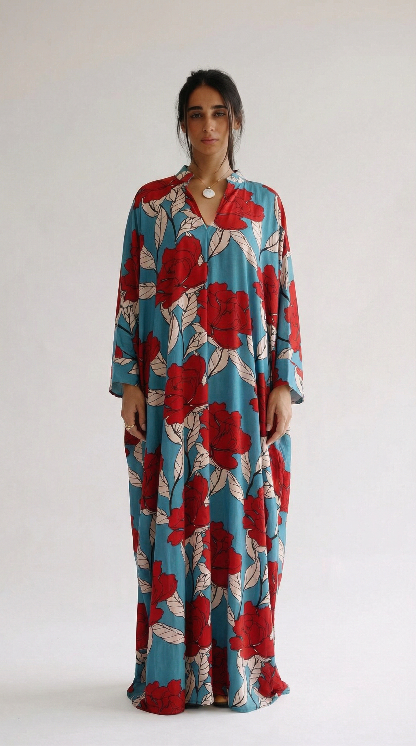 Woman wearing a long floral dress with red and blue pattern on a white background