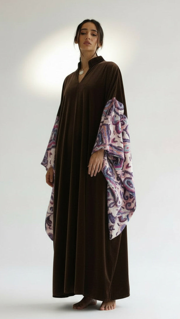 Woman wearing a long dark brown dress with floral sleeves on a white background