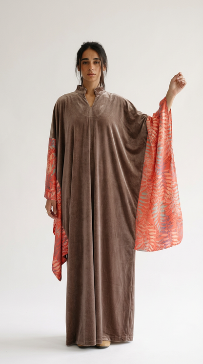 Person wearing a brown dress with orange accents on a white background